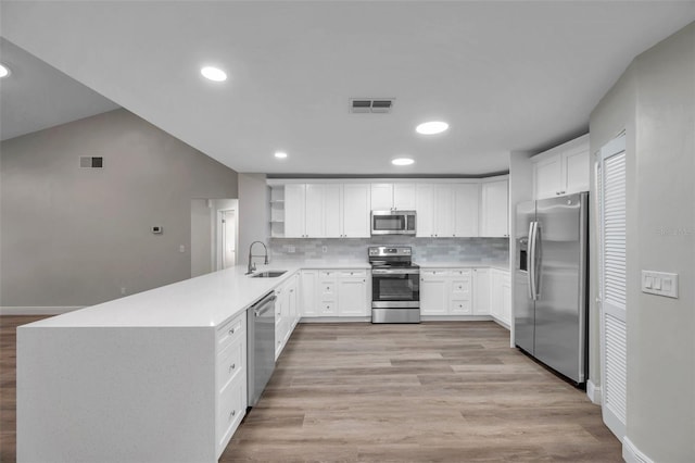 kitchen with sink, white cabinetry, appliances with stainless steel finishes, kitchen peninsula, and decorative backsplash