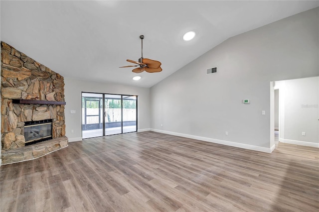 unfurnished living room featuring ceiling fan, high vaulted ceiling, a stone fireplace, and light hardwood / wood-style floors