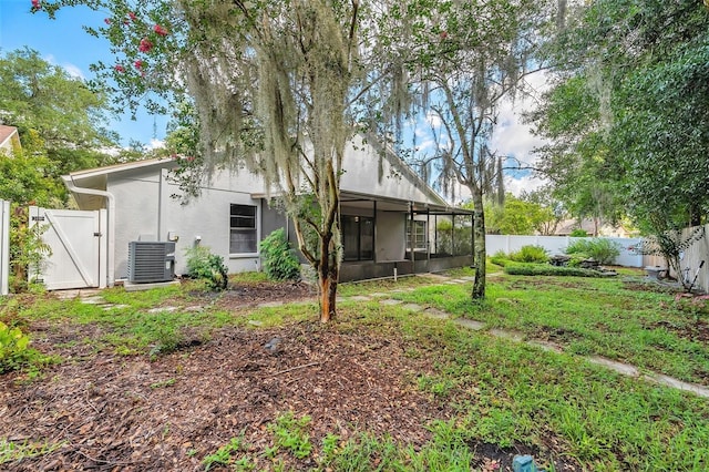 back of house with a yard and central AC