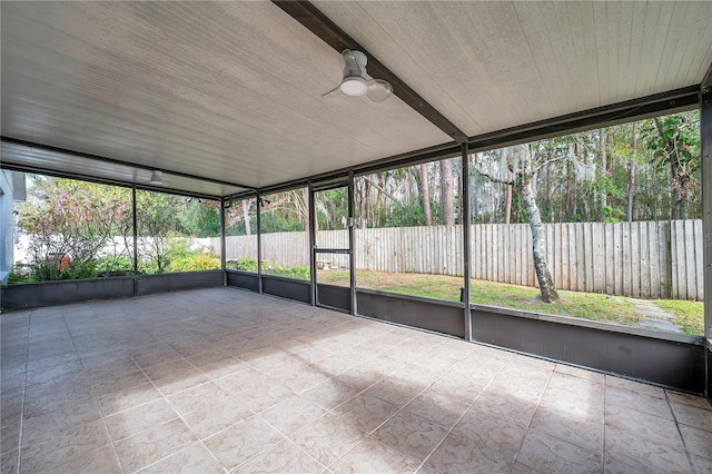 unfurnished sunroom with ceiling fan and beam ceiling