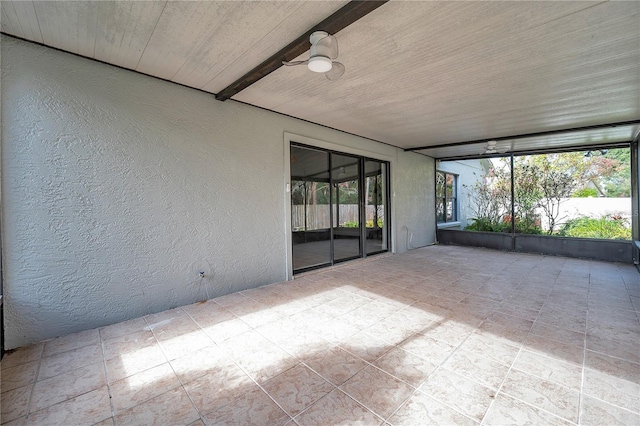 unfurnished sunroom featuring beamed ceiling and ceiling fan