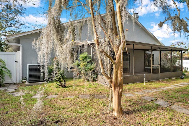 rear view of property with central AC unit, a lawn, and a sunroom