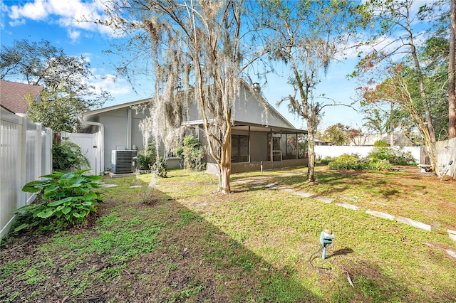 back of property featuring a sunroom, a yard, and central AC