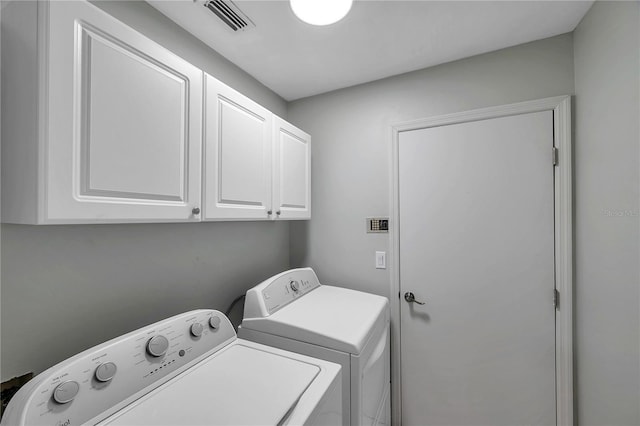 clothes washing area featuring cabinets and washing machine and clothes dryer