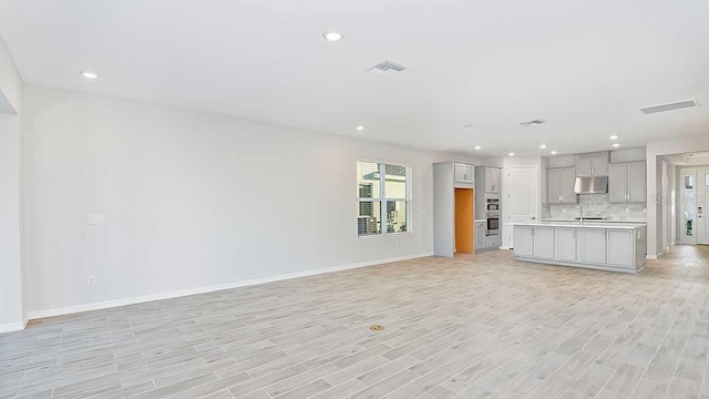 unfurnished living room featuring sink and light hardwood / wood-style flooring