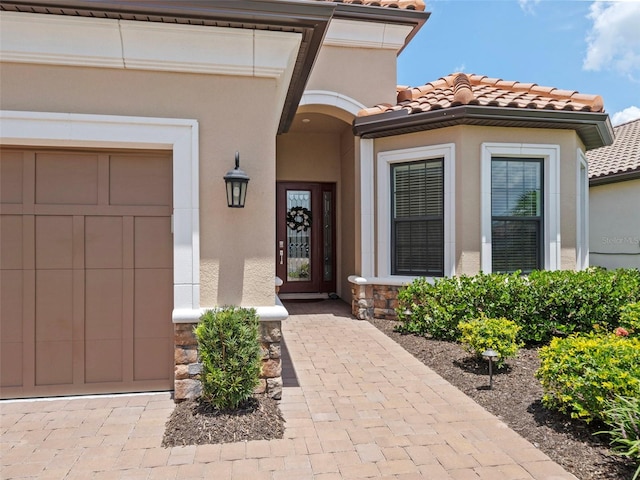 doorway to property with stone siding, a tile roof, and stucco siding