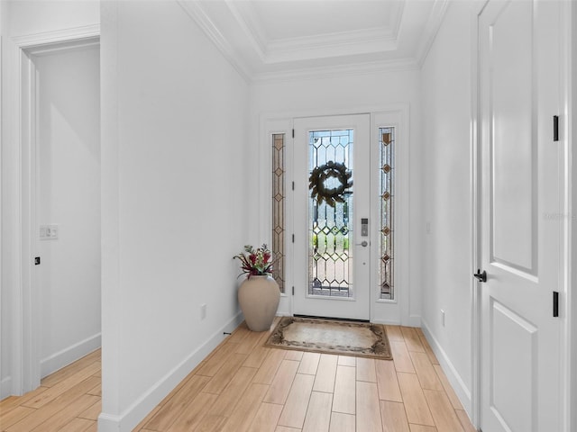 entrance foyer featuring baseboards, light wood finished floors, a raised ceiling, and crown molding