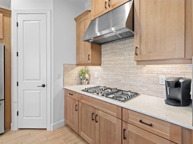 kitchen with light wood finished floors, stainless steel appliances, decorative backsplash, light stone countertops, and under cabinet range hood