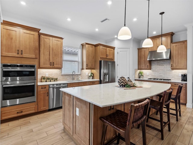 kitchen featuring pendant lighting, visible vents, appliances with stainless steel finishes, a kitchen island, and under cabinet range hood