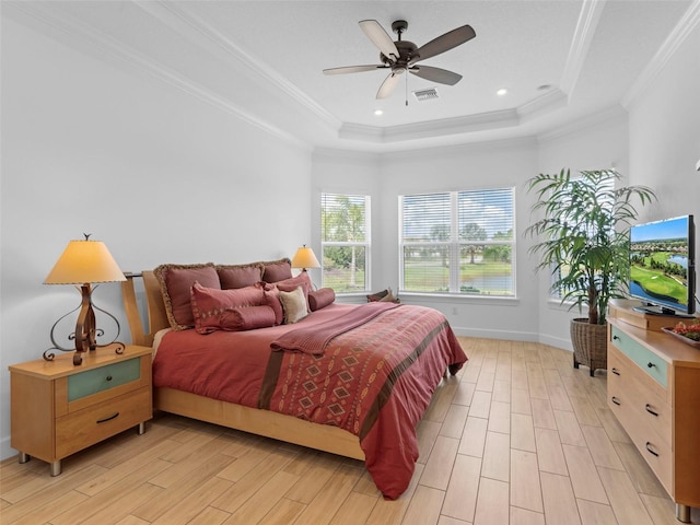 bedroom with light wood-style floors, visible vents, a raised ceiling, and crown molding