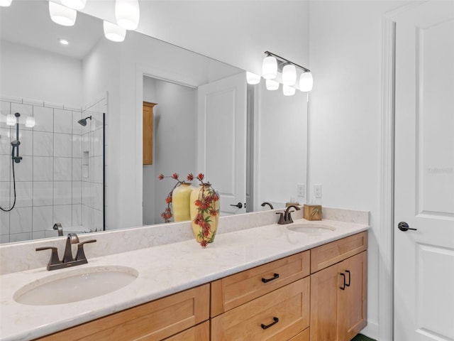 full bathroom with a tile shower, double vanity, and a sink