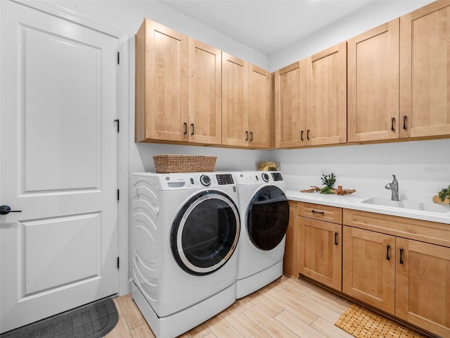 laundry area featuring a sink, washing machine and clothes dryer, cabinet space, and wood tiled floor