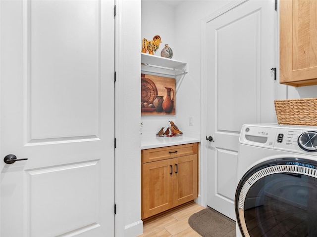 washroom featuring cabinet space, light wood-style flooring, and washer / clothes dryer