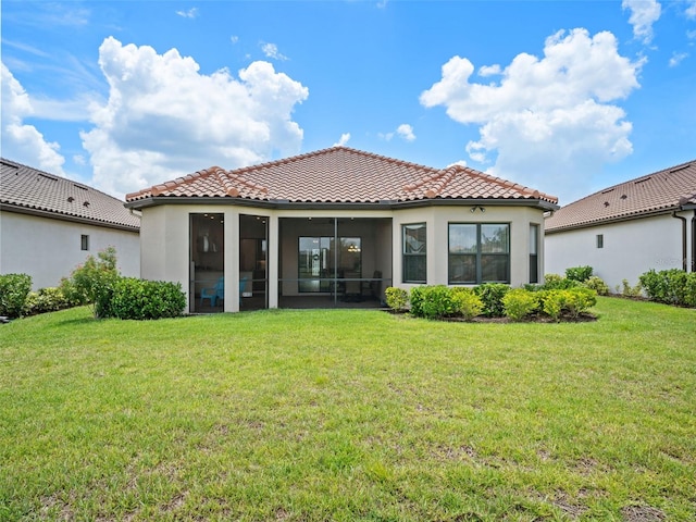 back of house with a sunroom, a tile roof, and a lawn