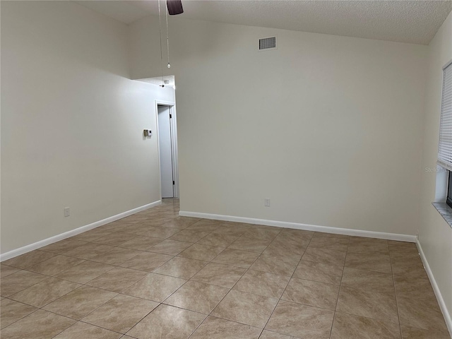 unfurnished room featuring a textured ceiling, ceiling fan, light tile patterned floors, and lofted ceiling