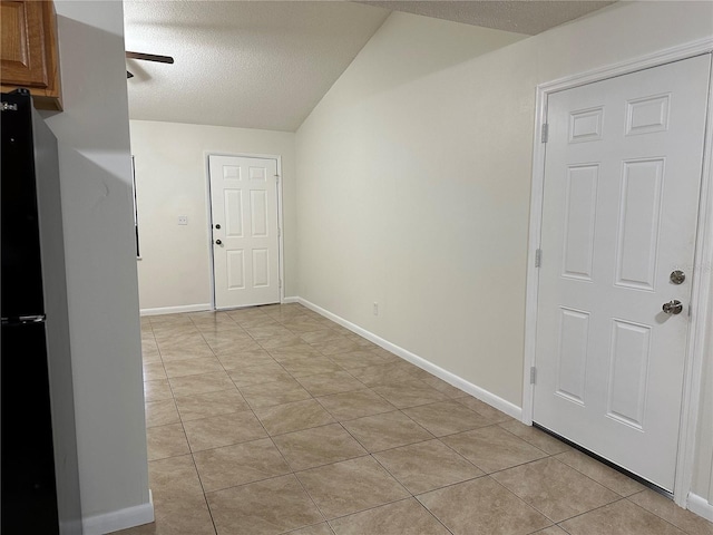 tiled entryway featuring lofted ceiling and a textured ceiling