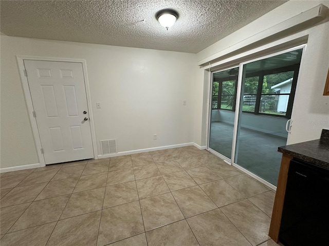 tiled empty room featuring a textured ceiling