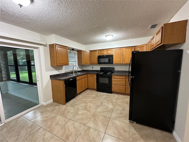 kitchen featuring sink, a textured ceiling, light tile patterned floors, and black appliances