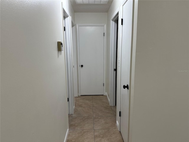 hallway featuring a textured ceiling and light tile patterned flooring