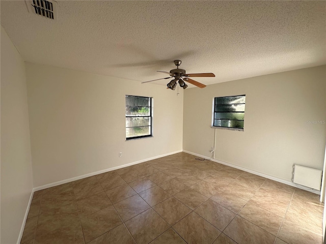 tiled empty room with ceiling fan and a textured ceiling