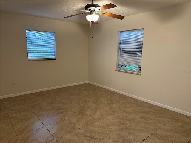 spare room featuring ceiling fan, a textured ceiling, and light tile patterned floors