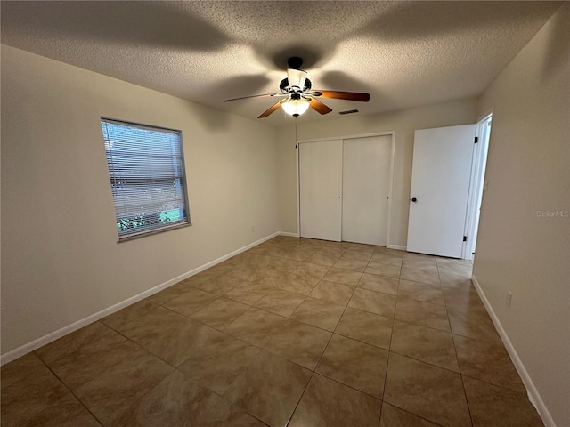 unfurnished bedroom with ceiling fan, a closet, light tile patterned flooring, and a textured ceiling