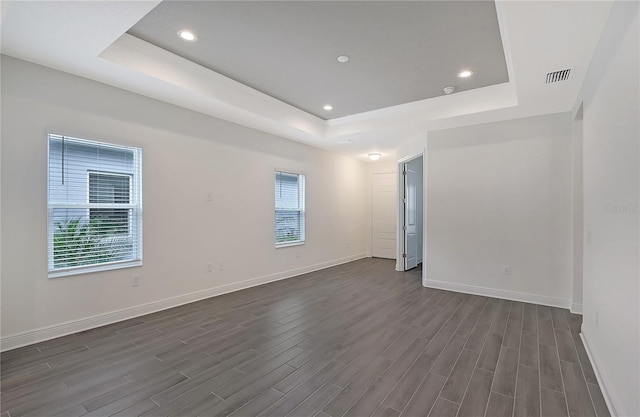 unfurnished room with dark hardwood / wood-style flooring and a raised ceiling