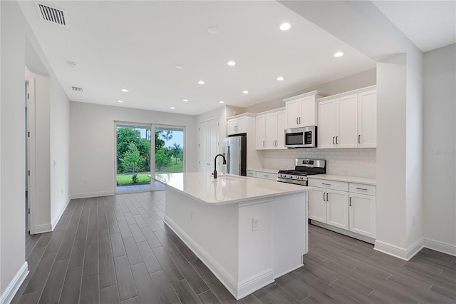 kitchen with backsplash, white cabinetry, a center island with sink, and appliances with stainless steel finishes