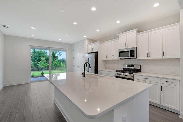 kitchen featuring sink, white cabinetry, stainless steel appliances, and an island with sink