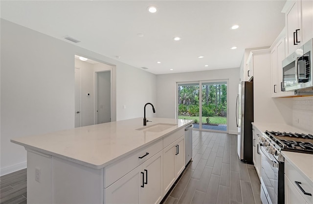 kitchen featuring white cabinetry, a kitchen island with sink, sink, and appliances with stainless steel finishes