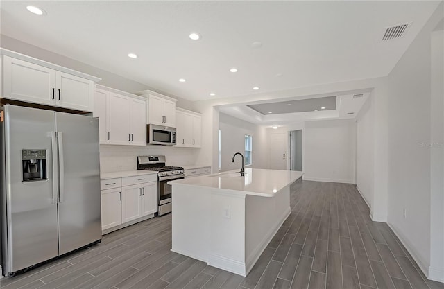 kitchen featuring sink, white cabinetry, stainless steel appliances, and an island with sink