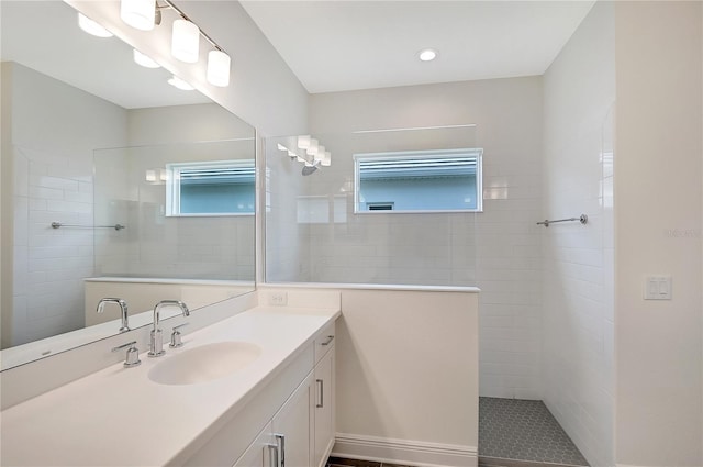 bathroom with a tile shower and vanity