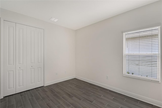 unfurnished bedroom featuring a closet and dark wood-type flooring