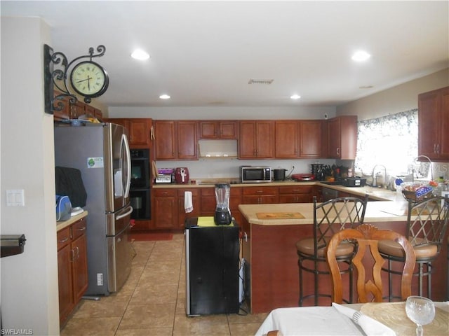 kitchen featuring a kitchen island, light tile floors, appliances with stainless steel finishes, sink, and a breakfast bar