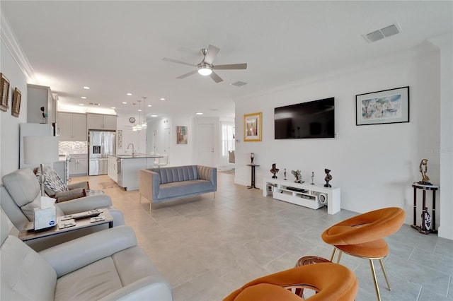 living room with ceiling fan, ornamental molding, and sink