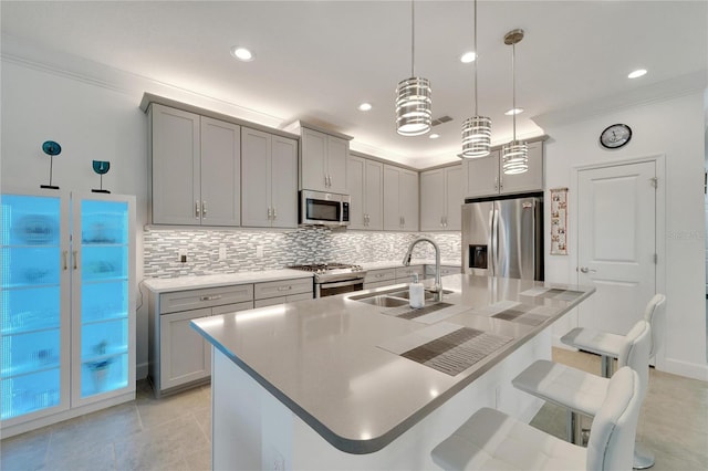 kitchen featuring pendant lighting, a kitchen breakfast bar, a kitchen island with sink, and appliances with stainless steel finishes