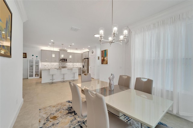 dining area with crown molding, light tile patterned floors, and an inviting chandelier