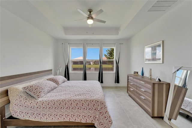 tiled bedroom with ceiling fan and a raised ceiling