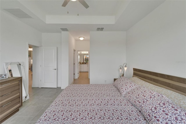 bedroom featuring ceiling fan, a raised ceiling, and ensuite bathroom