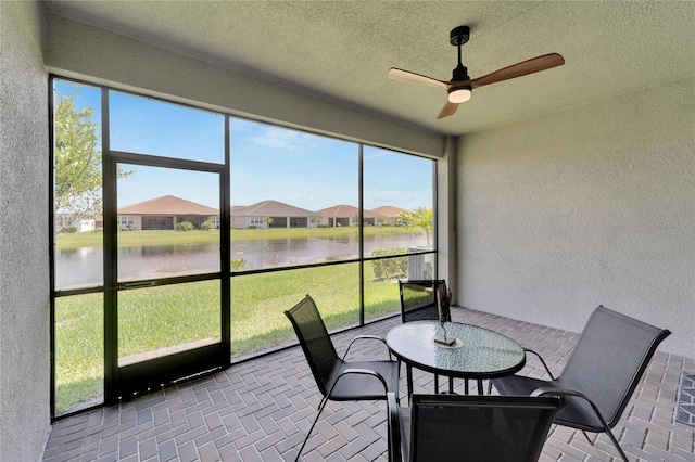 sunroom / solarium featuring ceiling fan and a water view