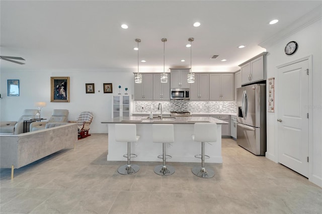 kitchen featuring appliances with stainless steel finishes, hanging light fixtures, a kitchen breakfast bar, and an island with sink