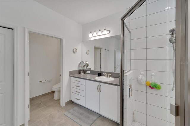 bathroom with walk in shower, tile patterned flooring, vanity, and toilet