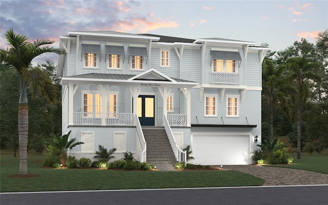 view of front of home featuring a balcony, a lawn, and a garage