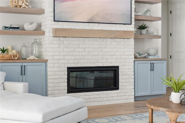 living room featuring a fireplace, built in features, and light hardwood / wood-style flooring