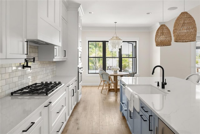 kitchen with white cabinets, pendant lighting, light stone countertops, and appliances with stainless steel finishes