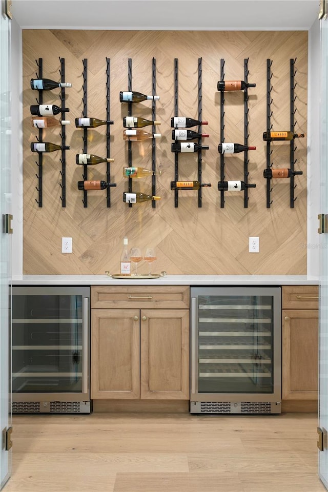 bar with wood walls, light hardwood / wood-style flooring, and beverage cooler