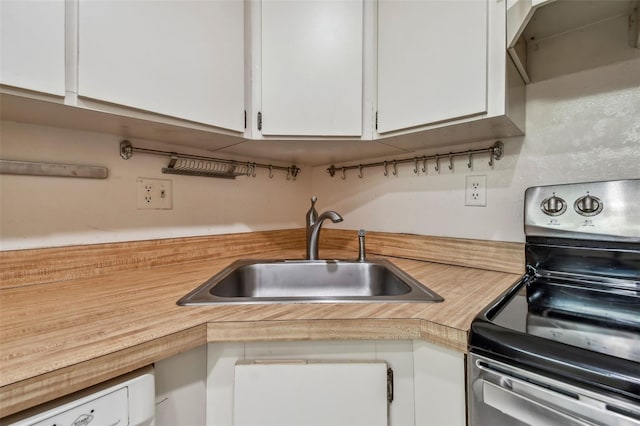 kitchen featuring stainless steel range with electric stovetop, white cabinetry, sink, and white dishwasher