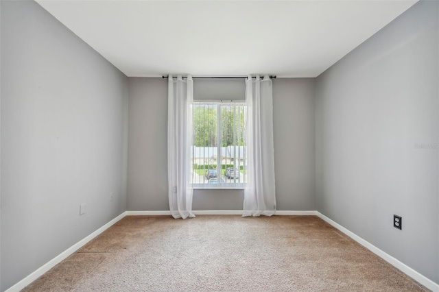 spare room featuring carpet and baseboards