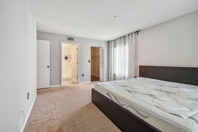 carpeted bedroom featuring a walk in closet, visible vents, and baseboards