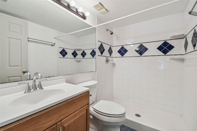 bathroom with tiled shower, vanity, and toilet